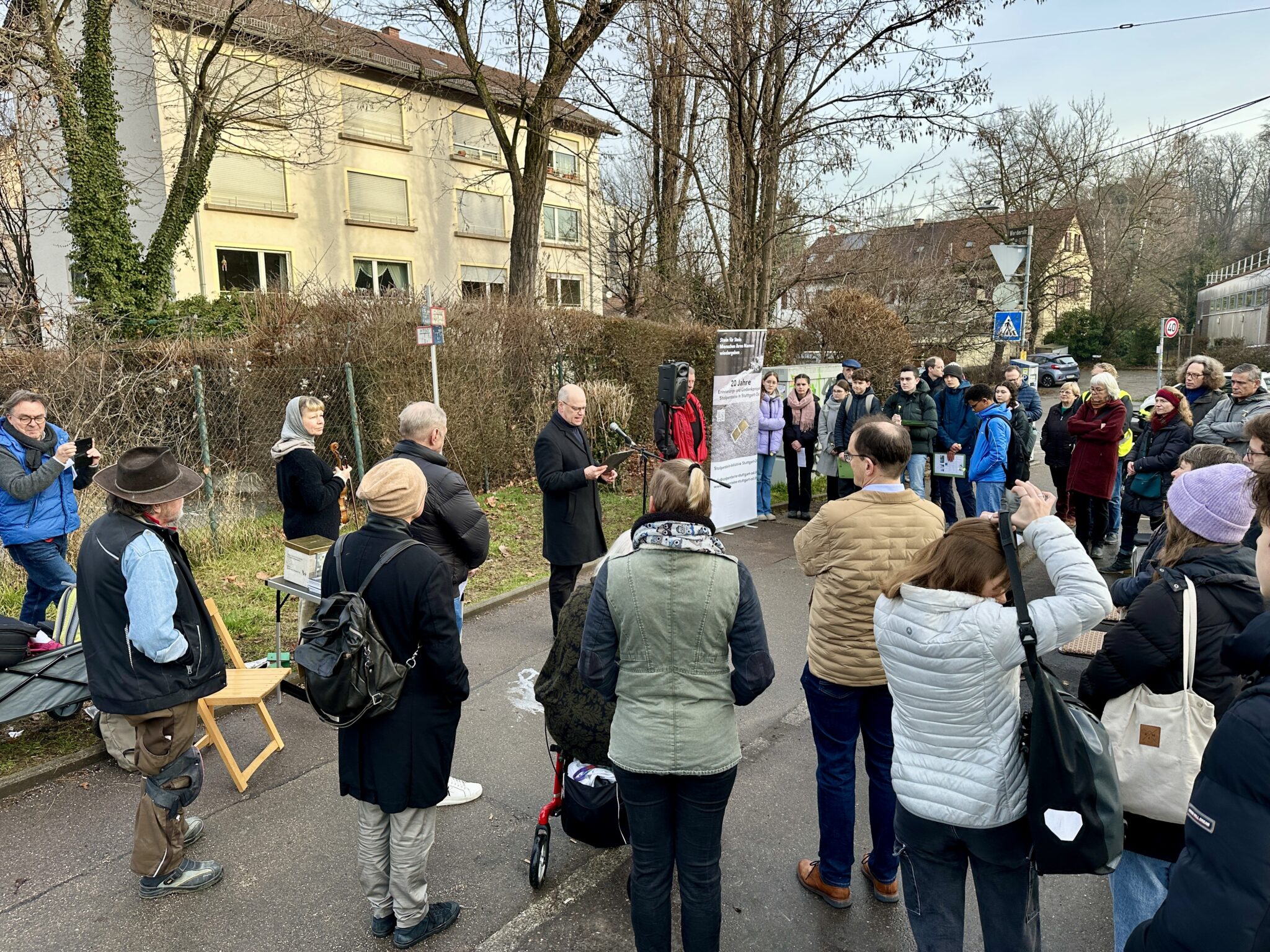 Personenmenge gedenkt Opfern des Nationalsozialismus mit dem Legen von Stolpersteinen