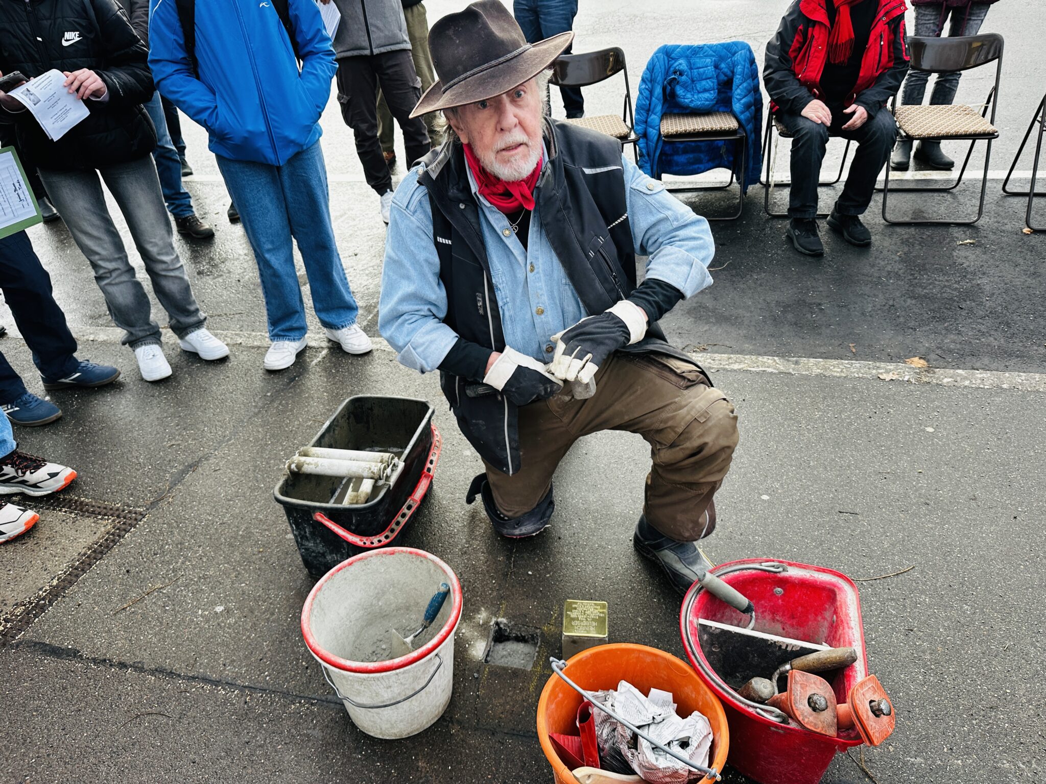 Mann platziert Stolpersteine im Gehweg