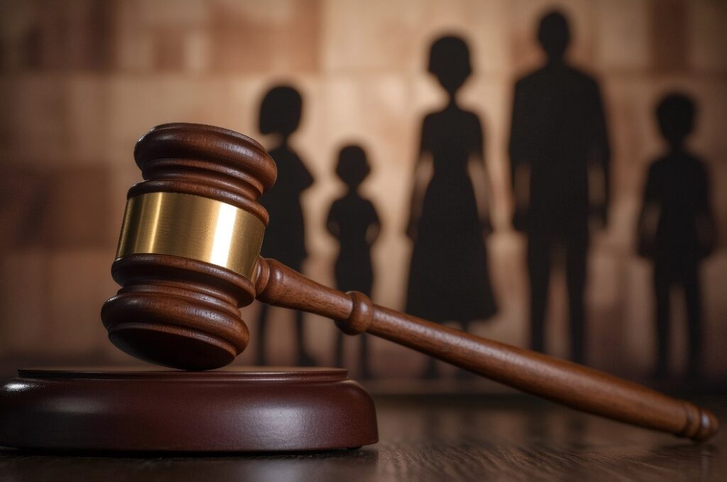 Der Hammer des Richters liegt auf dem Resonanzkörper mit der Familiensilhouette im Hintergrund, die das Sorgerecht für das Kind darstellt
