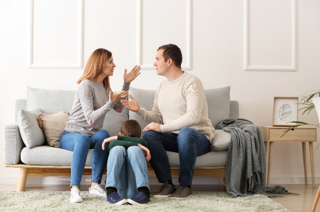 Trauriger kleiner Junge mit seinen streitenden Eltern zu Hause