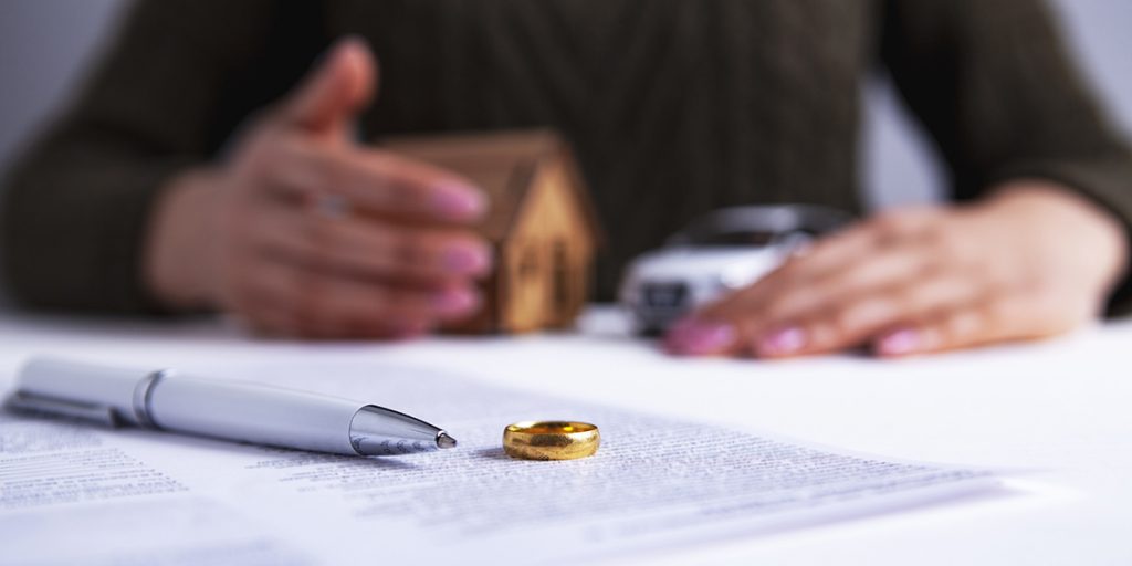 Person mit Scheidungspapieren und Ehering als Symbol für steigende Scheidungszahlen